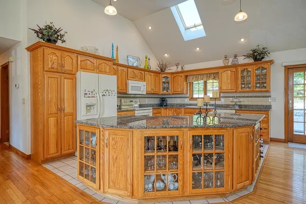 a kitchen with stainless steel appliances kitchen island granite countertop a refrigerator and a stove top oven
