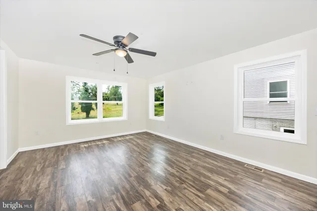 a view of an empty room with a window and wooden floor