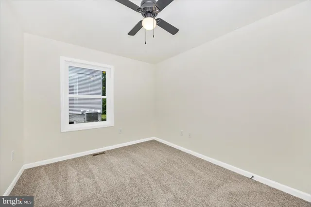 an empty room with a window and a ceiling fan