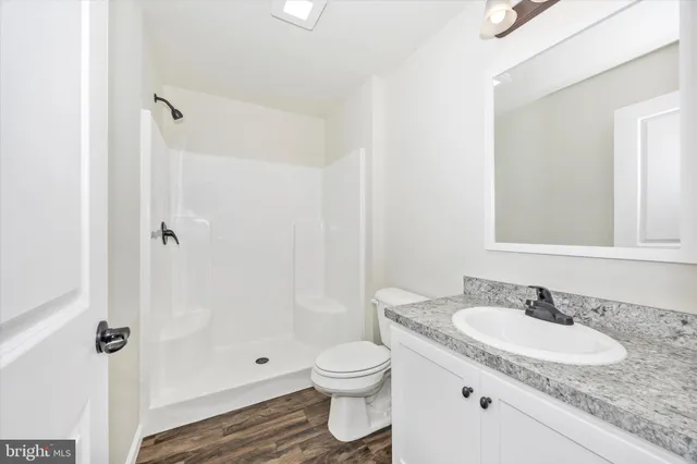 a bathroom with a granite countertop sink toilet a shower and a mirror