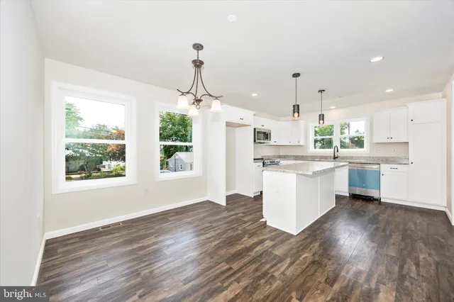 a kitchen with a refrigerator a sink dishwasher a stove and white cabinets with wooden floor