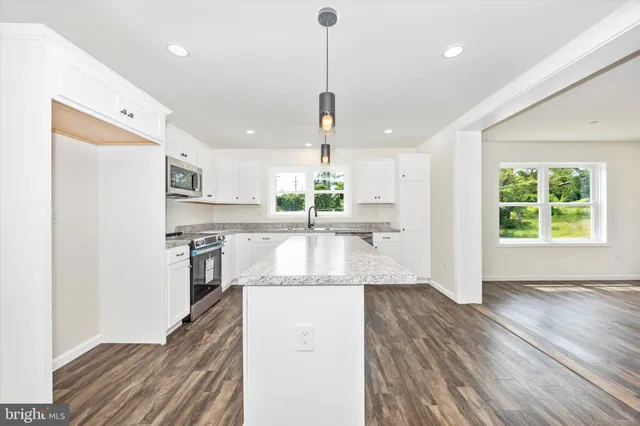 a kitchen with stainless steel appliances granite countertop a refrigerator a sink dishwasher a stove and white countertops with wooden floor