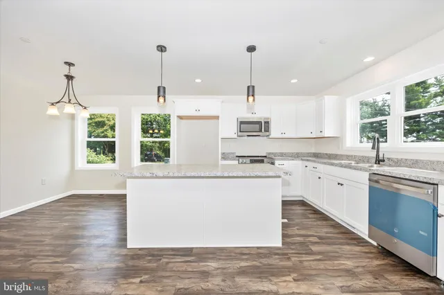 a kitchen with stainless steel appliances granite countertop a sink a stove a refrigerator and white cabinets