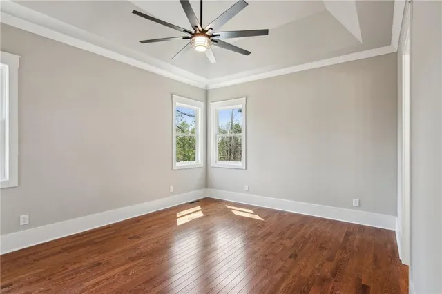 an empty room with wooden floor fan and windows