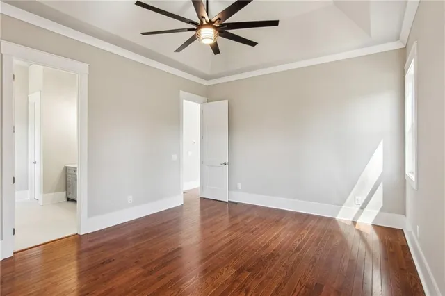 an empty room with wooden floor and a ceiling fan