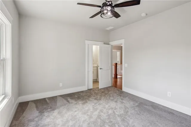 an empty room with a chandelier fan and windows