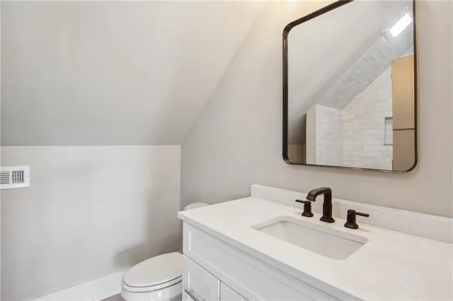 a bathroom with a granite countertop sink mirror vanity and toilet