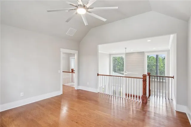 an empty room with wooden floor fan and windows