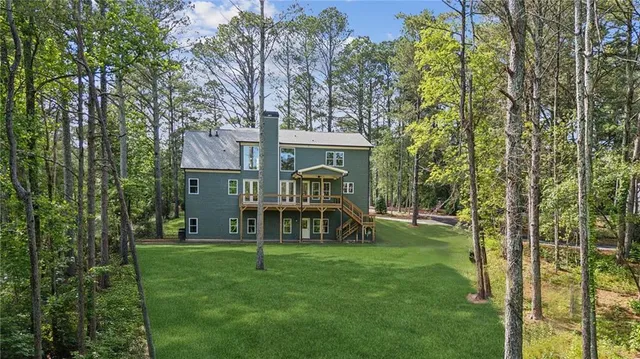 a view of a house with a big yard and large trees
