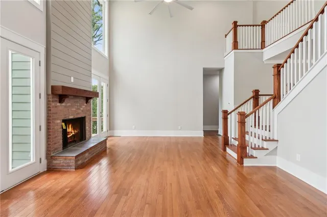 a view of an empty room with wooden floor fireplace and a window