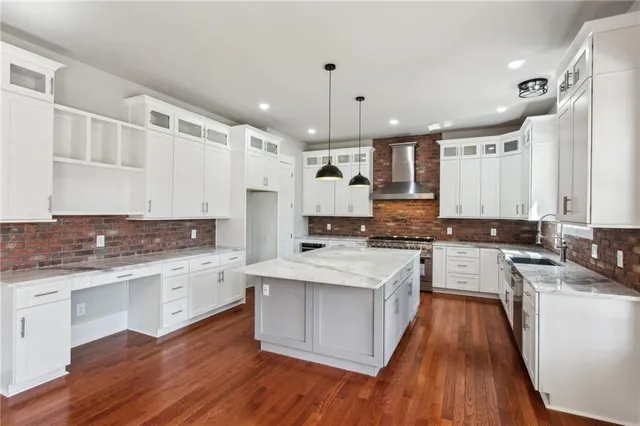 a large kitchen with a center island wooden floor and stainless steel appliances