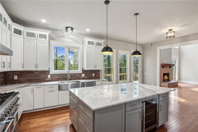 a kitchen with stainless steel appliances granite countertop a sink a stove and a wooden floors