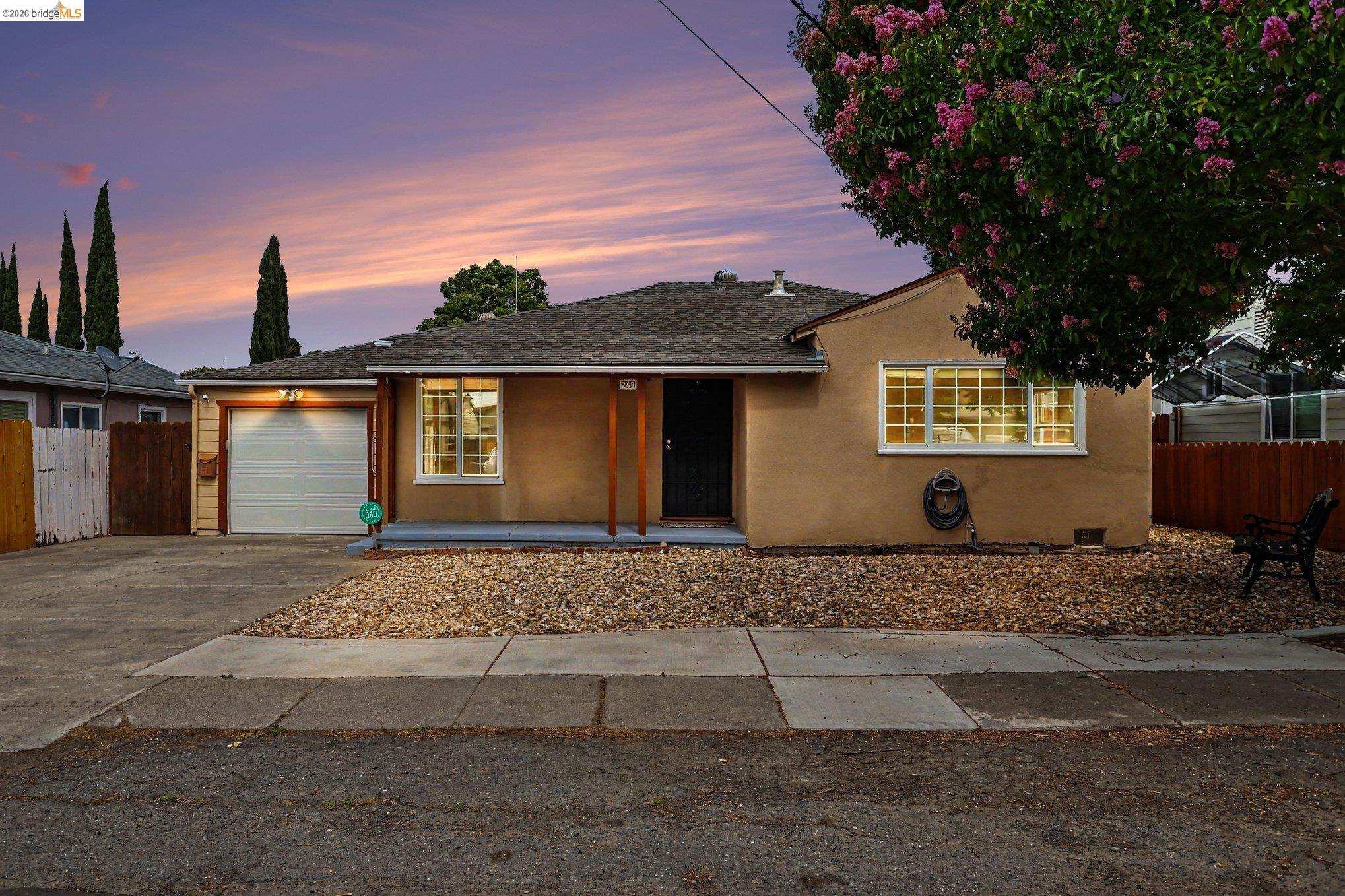 249 Madison Avenue Bay Point, CA 94565 - Photo 1 of 18 Single-story residence featuring a stucco exterior, attached garage with a roll-up door, covered front porch with wood columns, and a gravel front yard