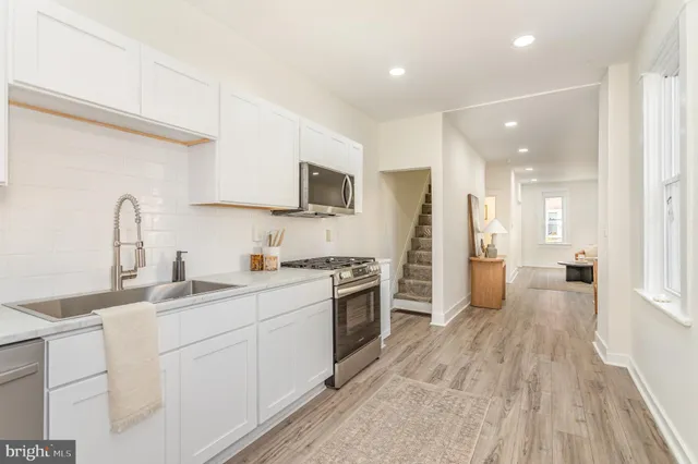 a kitchen with white cabinets appliances and sink