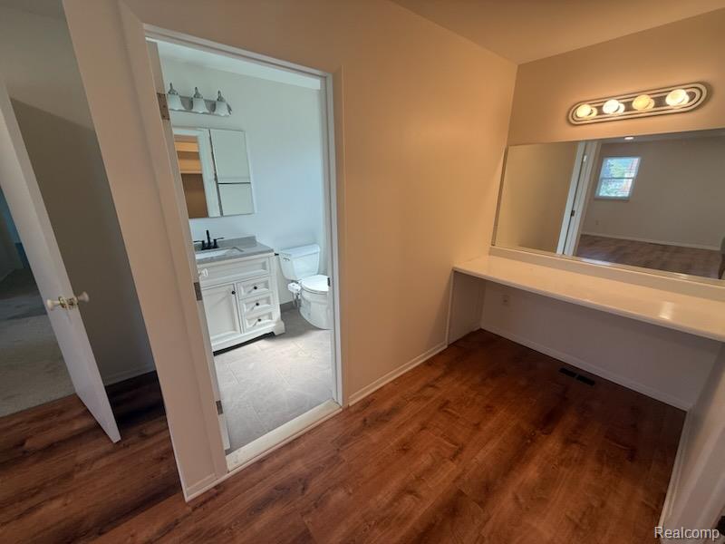 28144 Yorktown Road Farmington, MI 48331 - Photo 12 of 25 Vanity area featuring wood-finish flooring, a built-in countertop, and an integrated mirror with overhead lighting