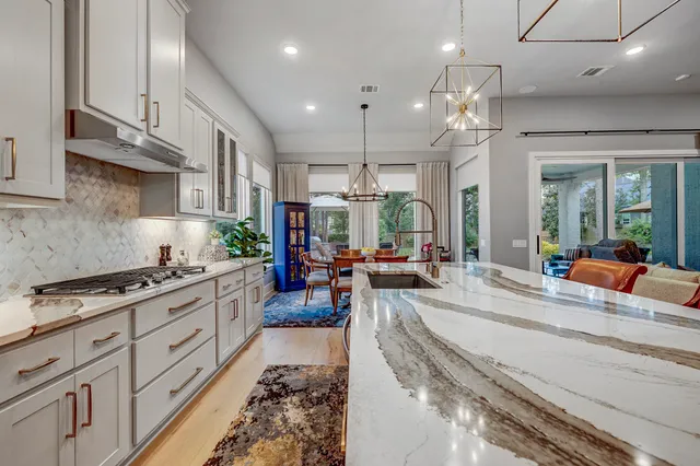 a kitchen with stainless steel appliances granite countertop wooden cabinets a sink dishwasher and a stove with wooden floor