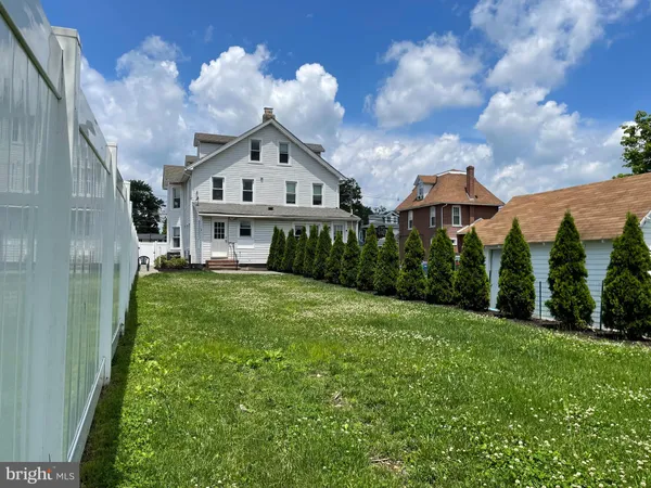 a view of a house with a big yard plants and large trees