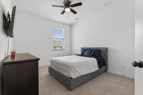 a bedroom with a bed and a flat tv screen on the dresser