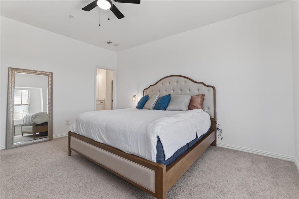3038 Opera Way Sachse, TX 75048 - Photo 24 of 31 a large bed sitting in a bedroom next to a window and a chandelier