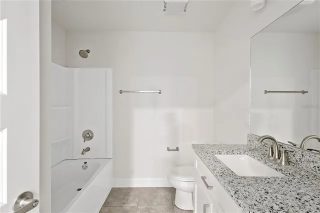 a bathroom with a granite countertop sink a toilet and bathtub