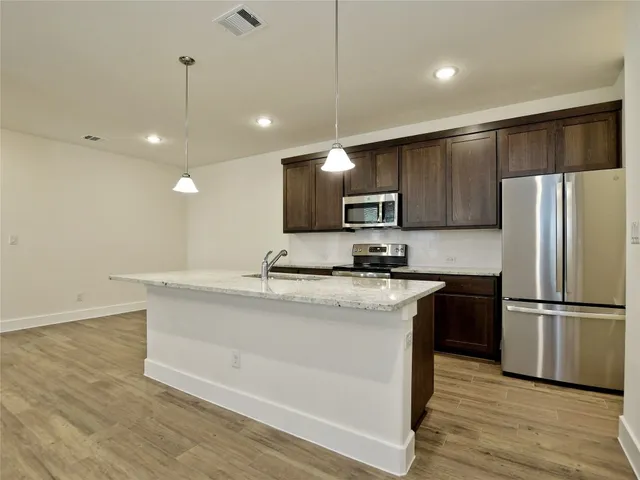 a kitchen with kitchen island a sink stainless steel appliances and wooden floor