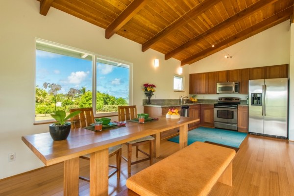 7561 Koolau Road, Unit B Kilauea, HI 96754 - Photo 11 of 25 a kitchen with stainless steel appliances kitchen island granite countertop a table chairs in it and wooden floor