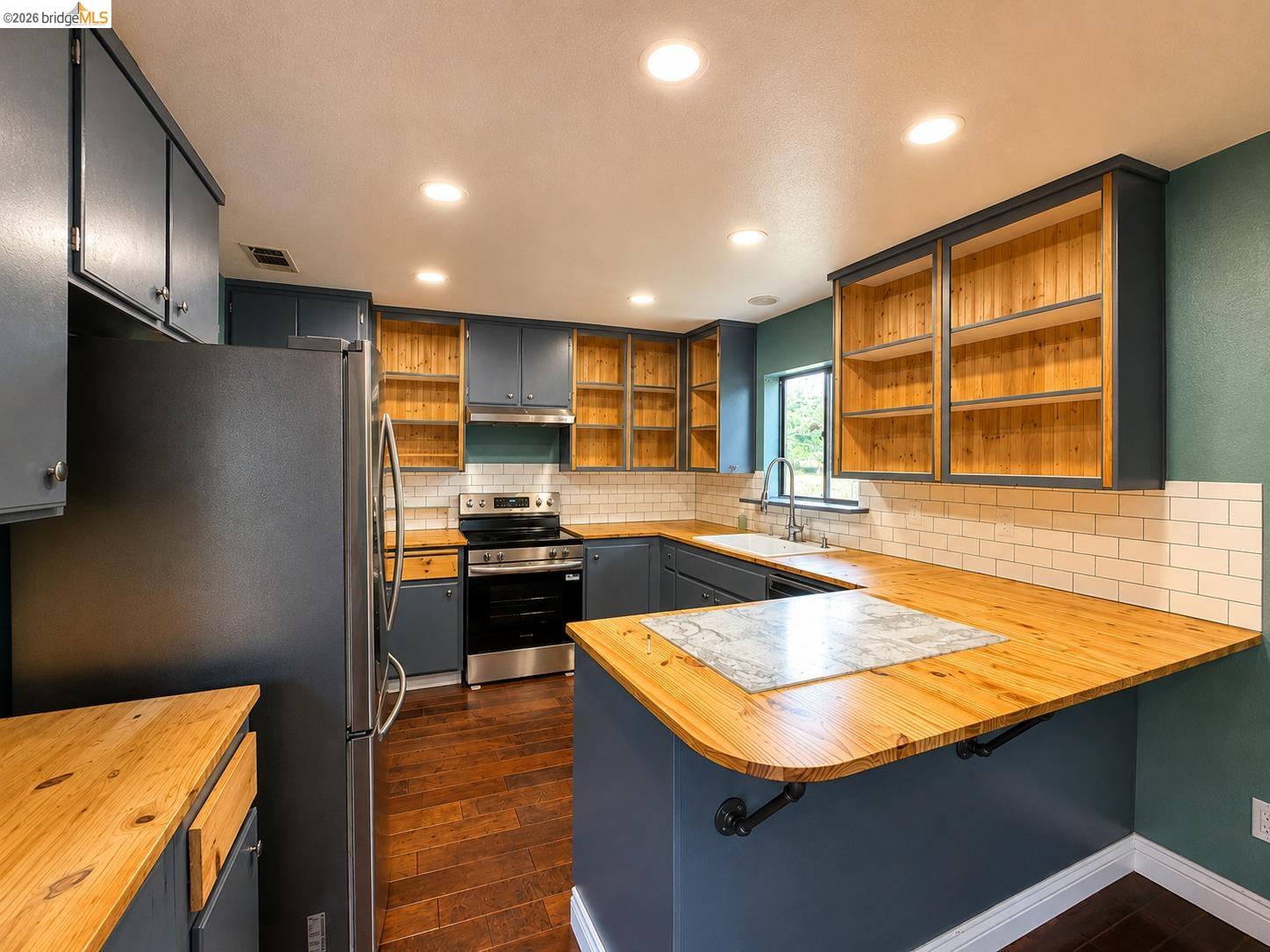20663 Ferretti Road Groveland, CA 95321 - Photo 6 of 41 Recessed lighting illuminates the kitchen featuring dark cabinetry, wood-finish countertops, and a white subway tile backsplash