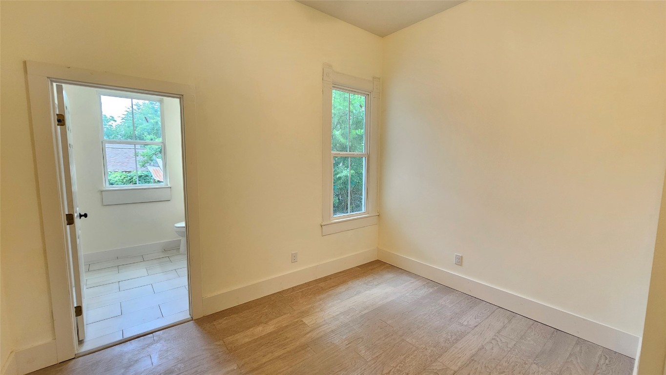 917 West 6th Street Taylor, TX 76574 - Photo 7 of 11 an empty room with wooden floor and windows