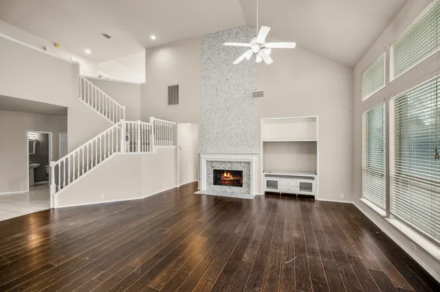 a view of a livingroom with wooden floor a ceiling fan and windows