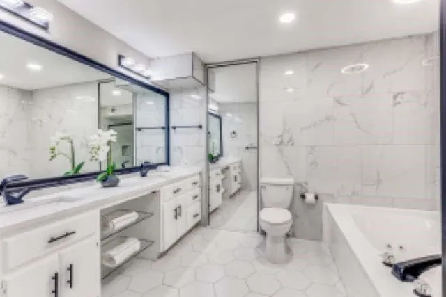 a bathroom with a double vanity sink toilet mirror and bathtub