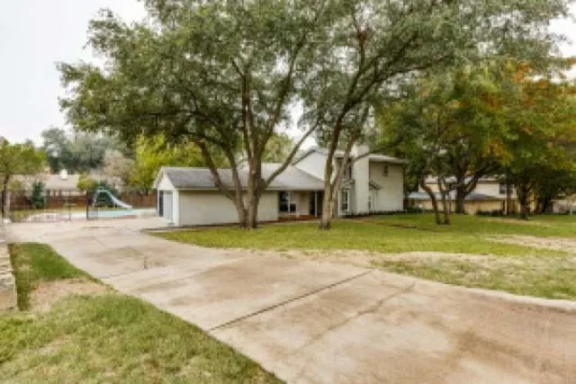 a view of a house with a yard and large trees