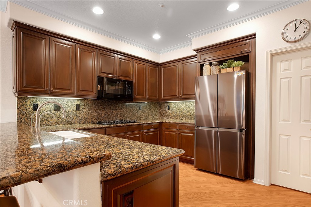 3 Avenida Cristal San Clemente, CA 92673 - Photo 11 of 36 a kitchen with stainless steel appliances granite countertop a refrigerator a stove and a sink with wooden floor