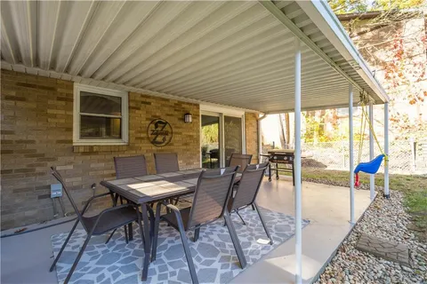 a roof deck with a dining table and chairs and potted plants