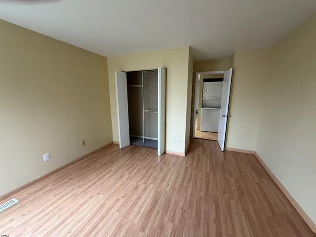 a view of an empty room with wooden floor and closet