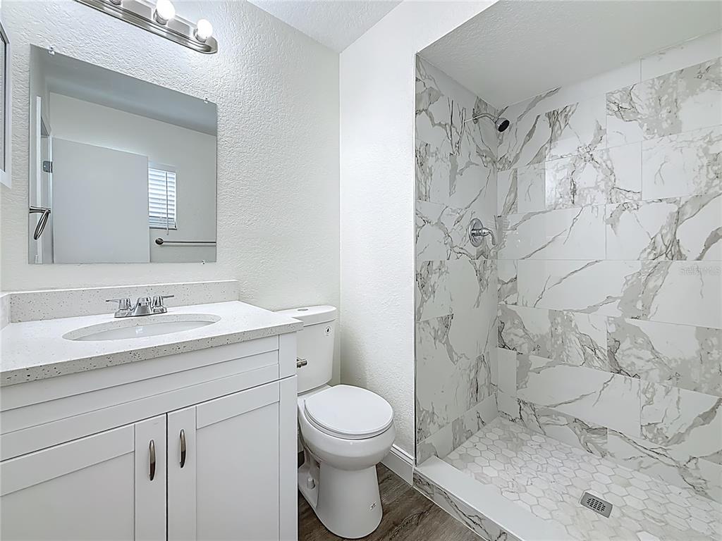 7480 118th Terrace Largo, FL 33773 - Photo 34 of 49 a bathroom with a granite countertop sink toilet a mirror and shower