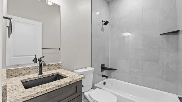 a bathroom with a granite countertop sink a toilet and bathtub