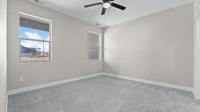 a view of empty room with wooden floor and ceiling fan