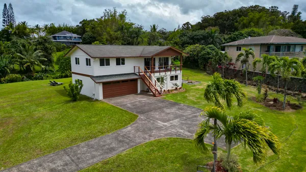 a view of a house with a big yard plants and large trees
