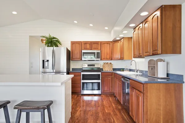 a kitchen with stainless steel appliances granite countertop a refrigerator a stove top oven a sink and dishwasher