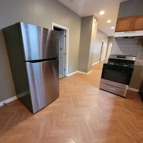 a view of an empty room with wooden floor and a bathroom