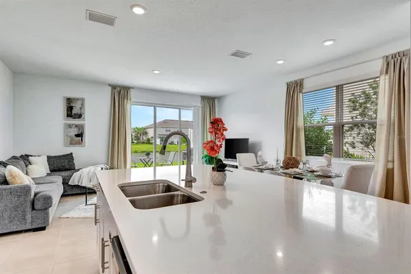 a living room with furniture a large window and dining table