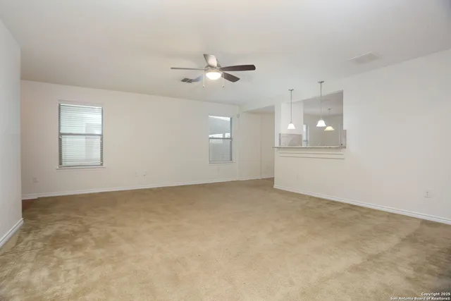 an empty room with windows and ceiling fan view