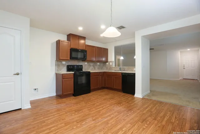 a kitchen with stainless steel appliances granite countertop a refrigerator a sink a stove a microwave and wooden floor