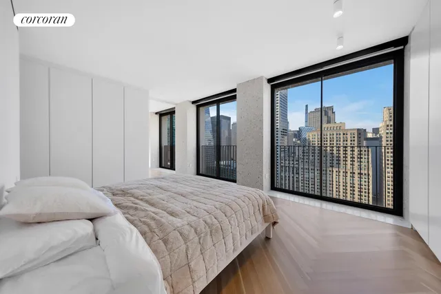 a large white open kitchen with stainless steel appliances kitchen island a stove a refrigerator a oven and a dining table with wooden floor