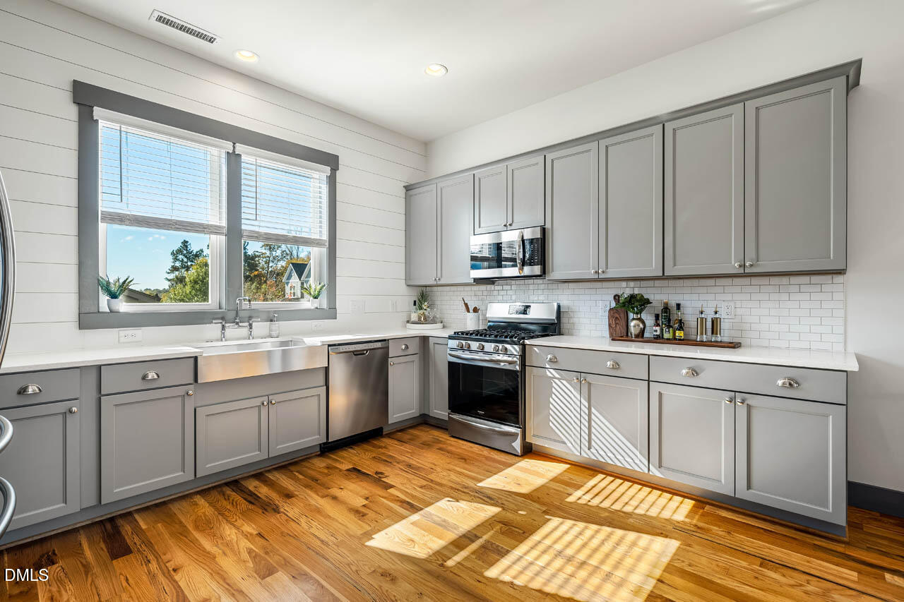 260 Quarter Gate Trace Chapel Hill, NC 27516 - Photo 15 of 68 a kitchen with stainless steel appliances granite countertop a stove top oven a sink dishwasher and white cabinets with wooden floor