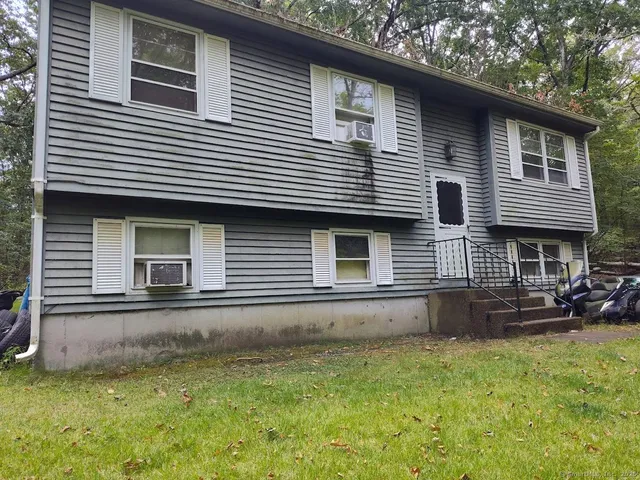 a view of a house with a yard and a large tree