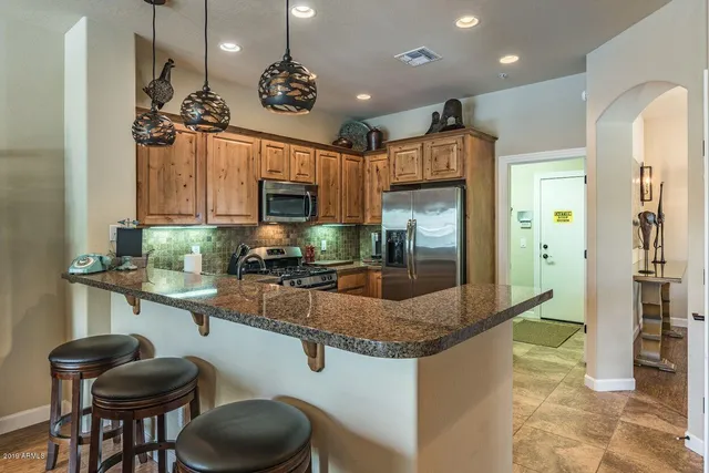 a kitchen with stainless steel appliances granite countertop a sink a stove and a refrigerator
