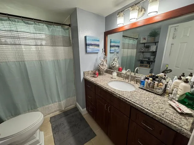 a bathroom with a granite countertop shower sink vanity and toilet