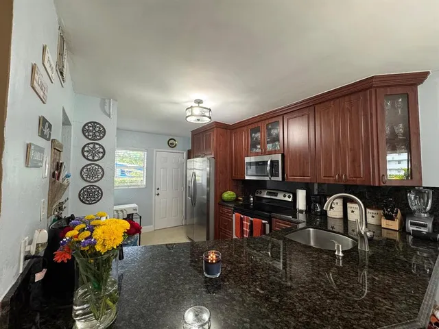 a kitchen with stainless steel appliances granite countertop a refrigerator a stove and a sink