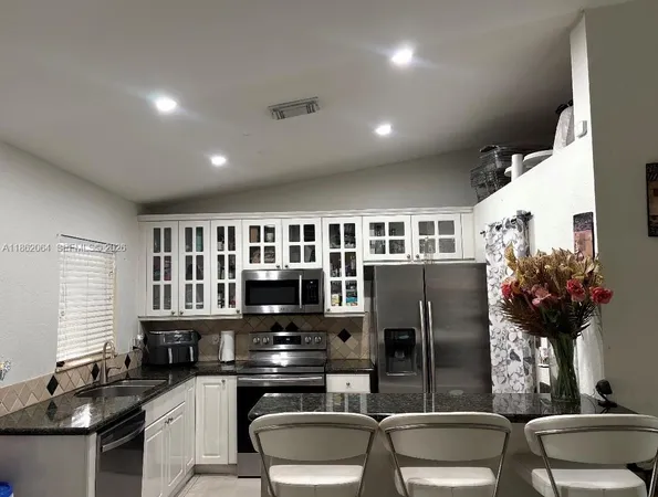 a kitchen with stainless steel appliances granite countertop a refrigerator and a stove